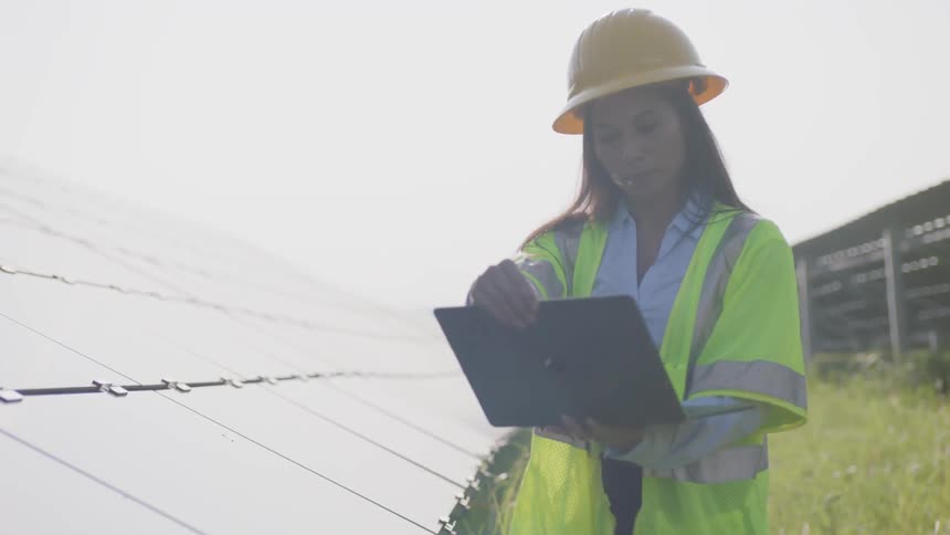 A young woman in a hard hat looks at her laptop
