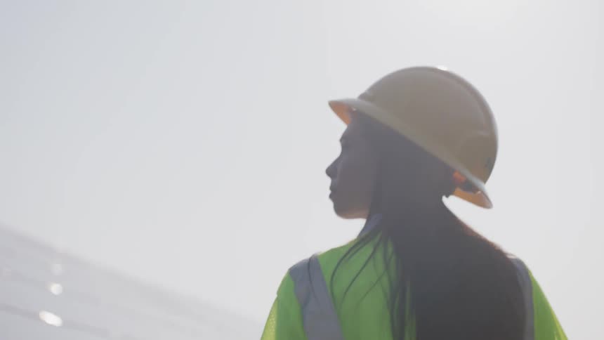 A woman walks with a hard hat on