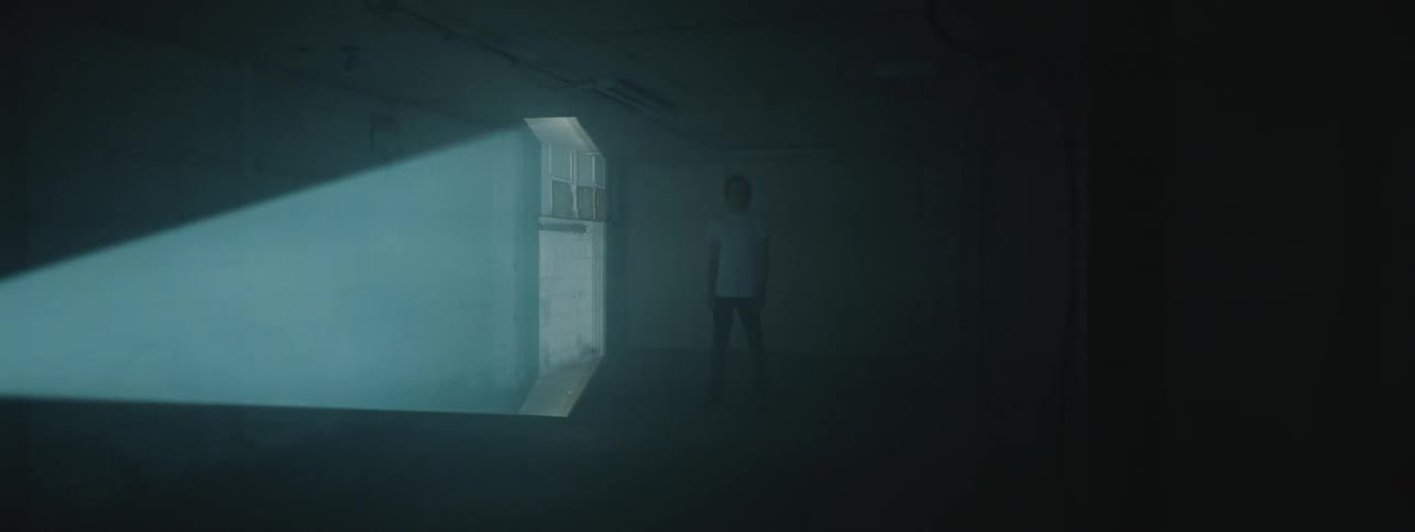 A man standing in the middle of a room while a light scans past him