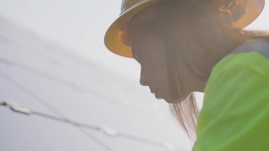 A woman wearing construction gear works on a solar panel