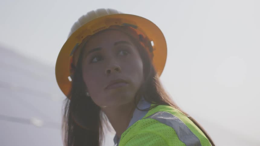 Woman in a hard hat supervising a solar panel array