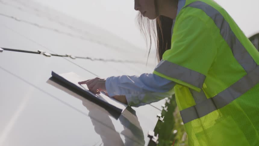 A female construction worker viewing papers on material outside