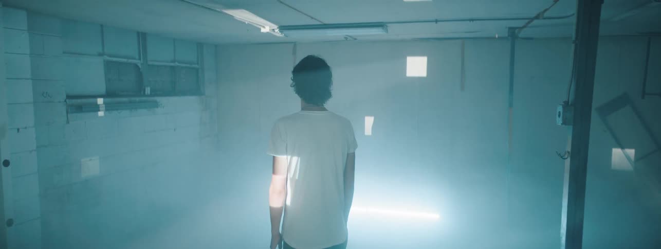 A man stands in a foggy room with flashing lights