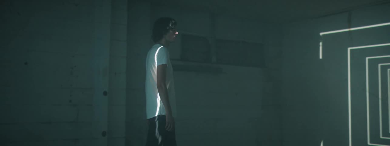 Teenage boy walks through industrial building with graphic lights