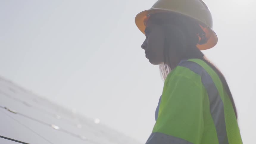 Woman in construction vest unrolls paper onto solar panels