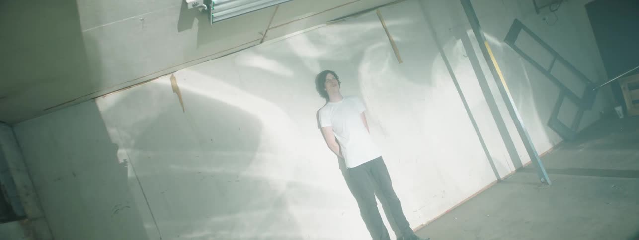 A man is leaning against the wall with projector imagines shining on him