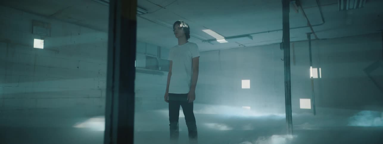 Teenage boy stands in empty room with square strobe light and fog effects