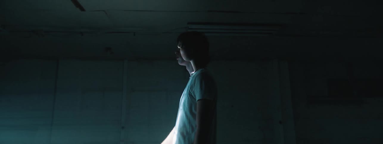 Man stands in dark room reaching toward strobing light source