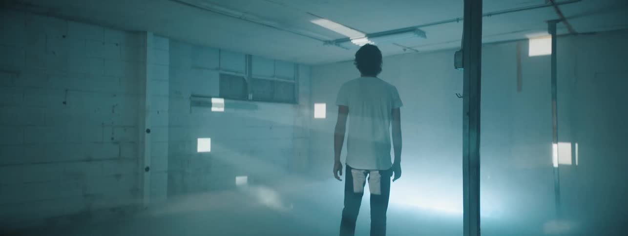 Man stands in room turning to look at light patterns
