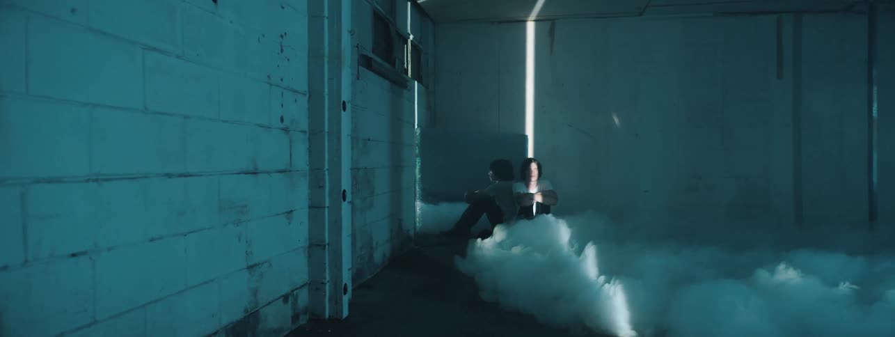 A person sits in a room as it fills with smoke