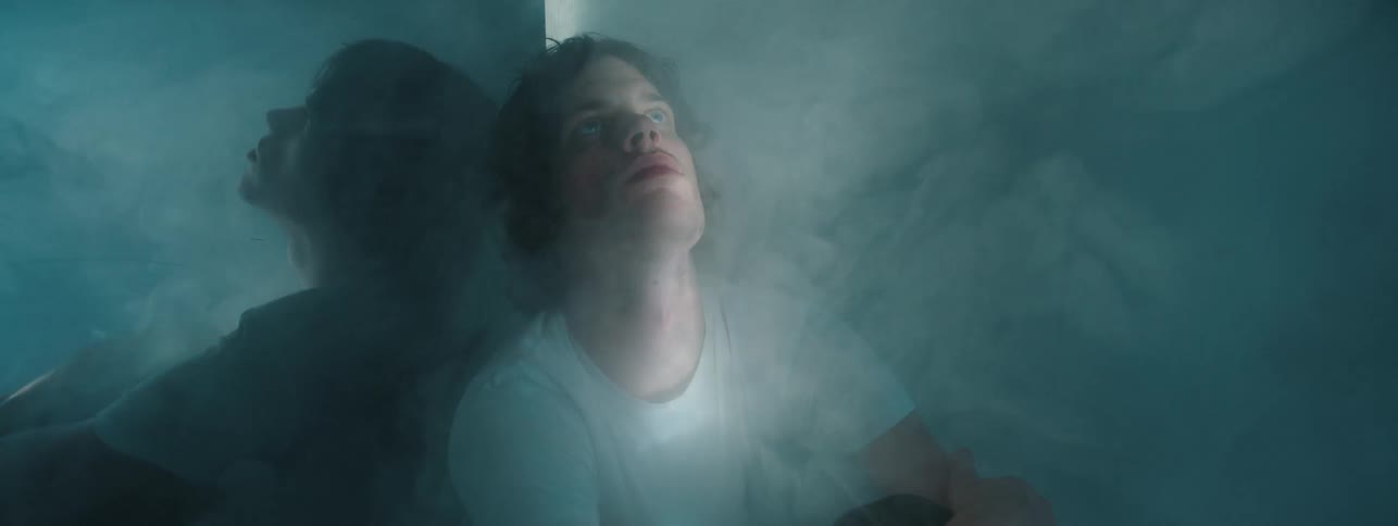 A man sits in a room full of smoke
