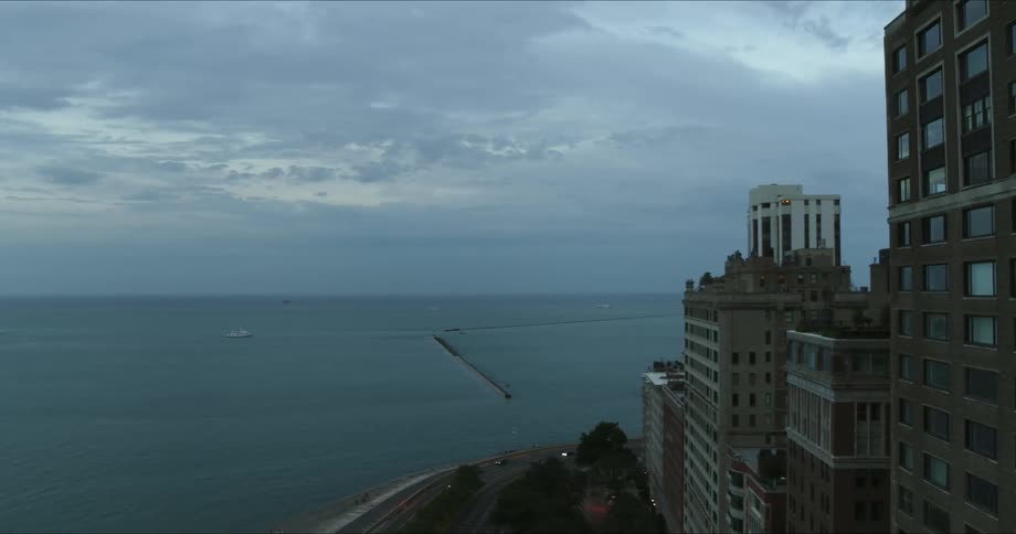 Vehicles drive around buildings by the coast of the city
