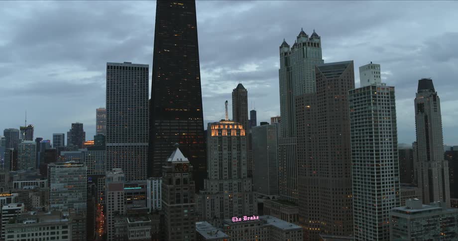 The drake hotel sign glows in the chicago skyline on a cloudy day