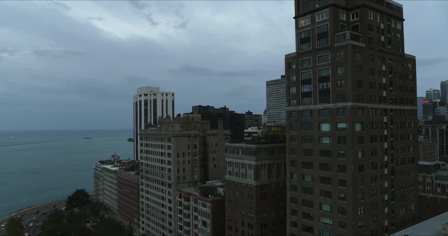 A city skyline near a large lake on an overcast evening
