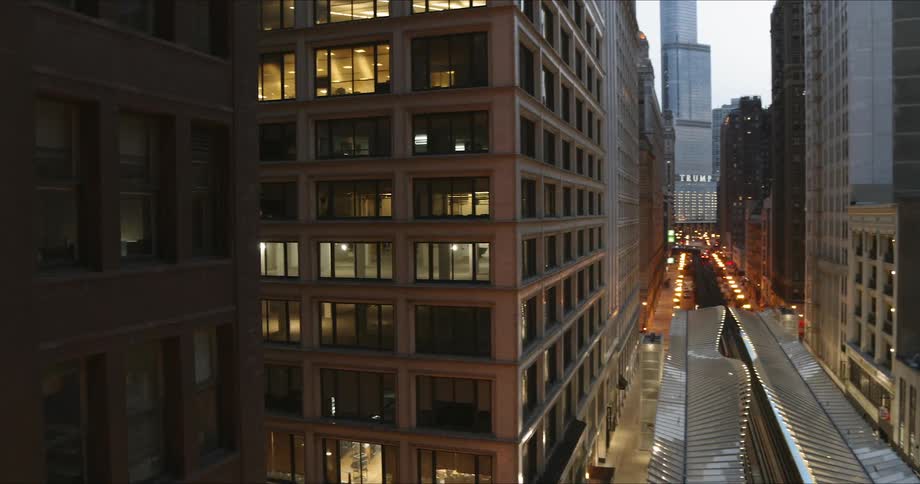 Tracks and platform of an elevated train in the heart of a city surrounded by buildings and streets