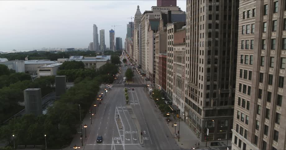 People are driving on the road past the buildings in the city