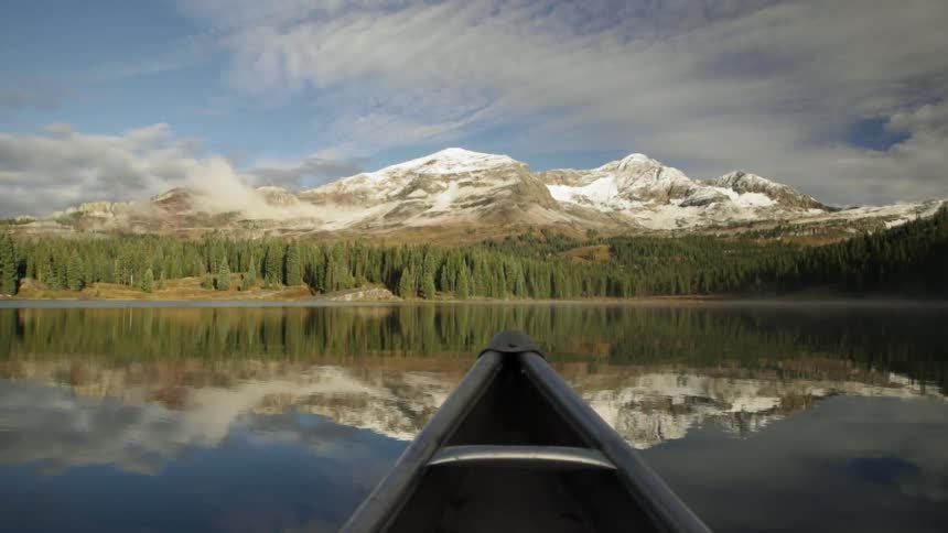 A boat sails across a river with mountains in the distance