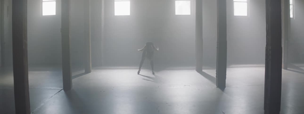 A woman is dancing in the dark hall