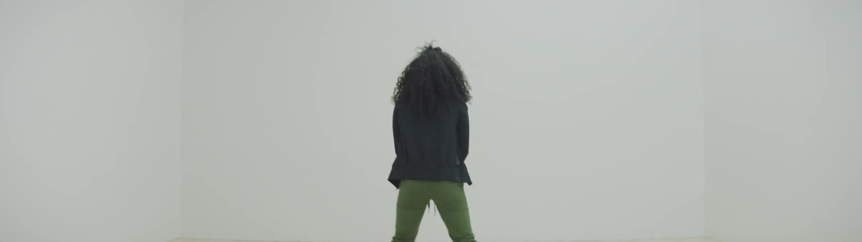 Curly hair girl dances between four white walls