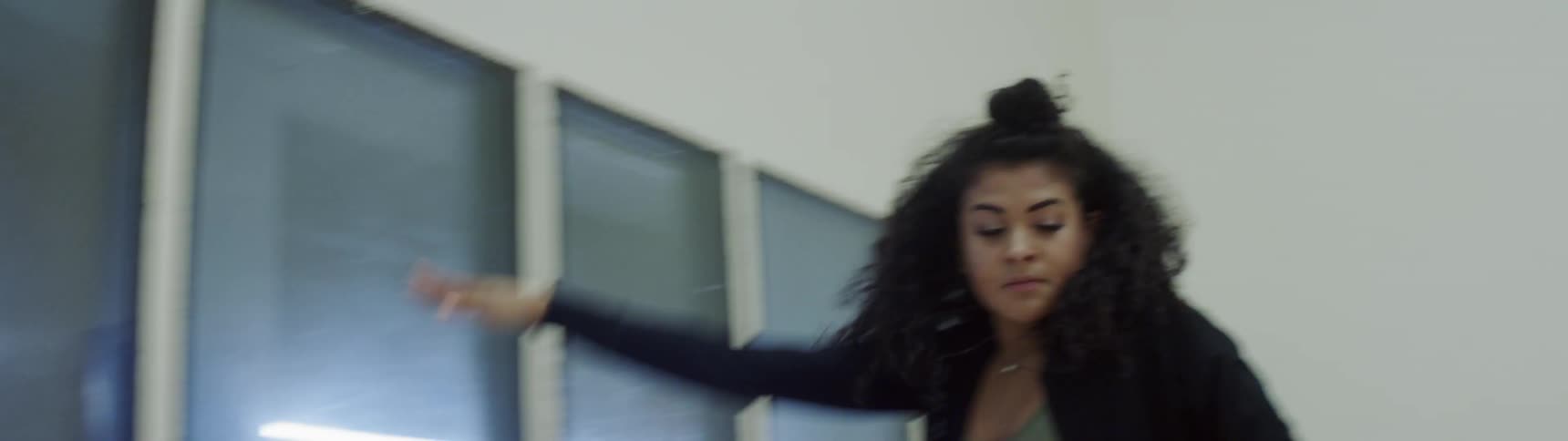 A black teenager pushes herself off a window and walks across the room