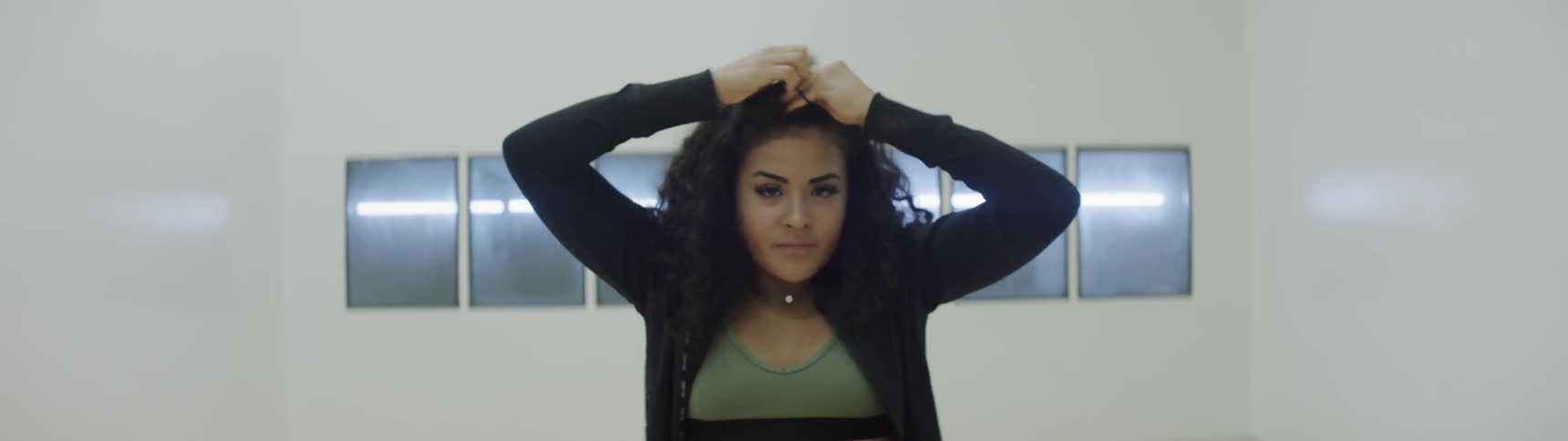 A woman ties up her hair while walking forward