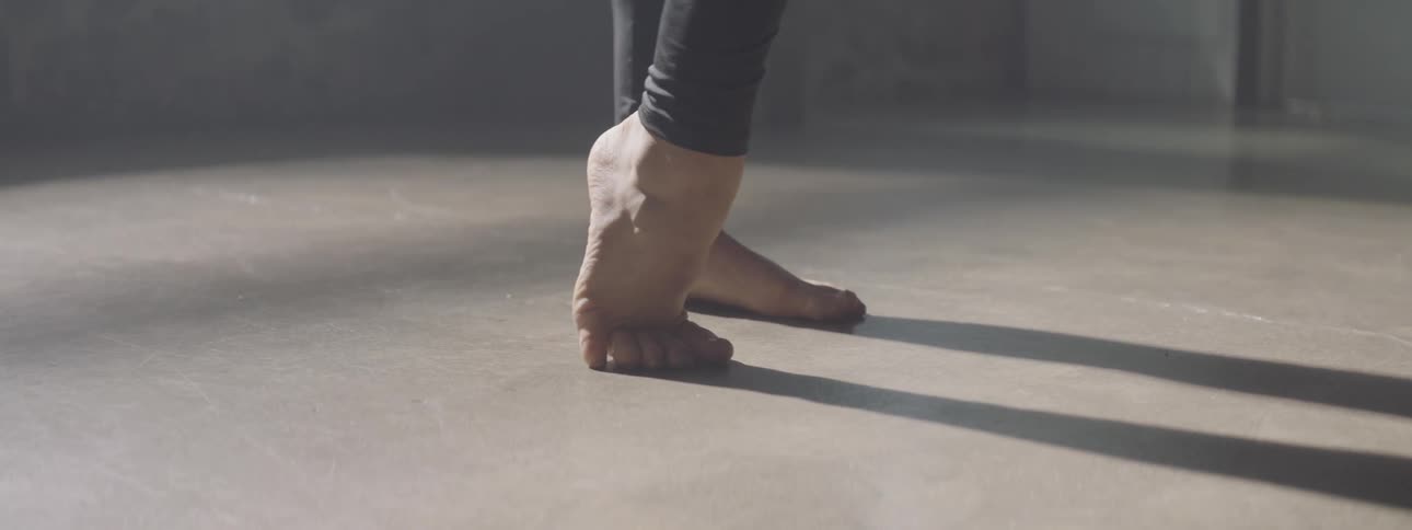 A dancer warms up their feet with stretching