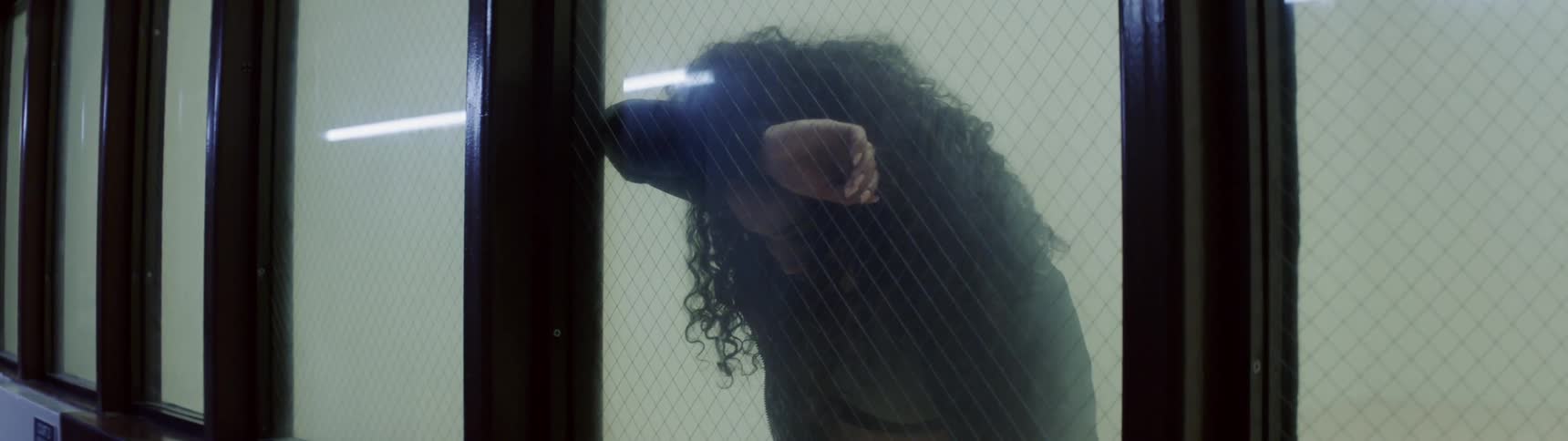 A woman leans against a glass window