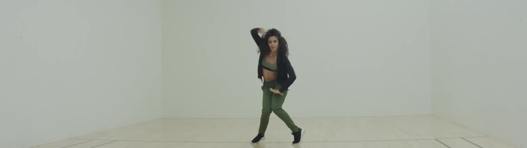 A woman hip hop dancing in a large white room