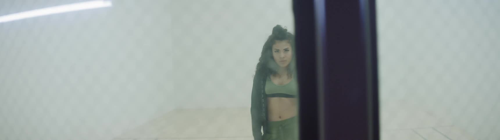 A teenage girl seen through window panes swings her arms and breathes heavily