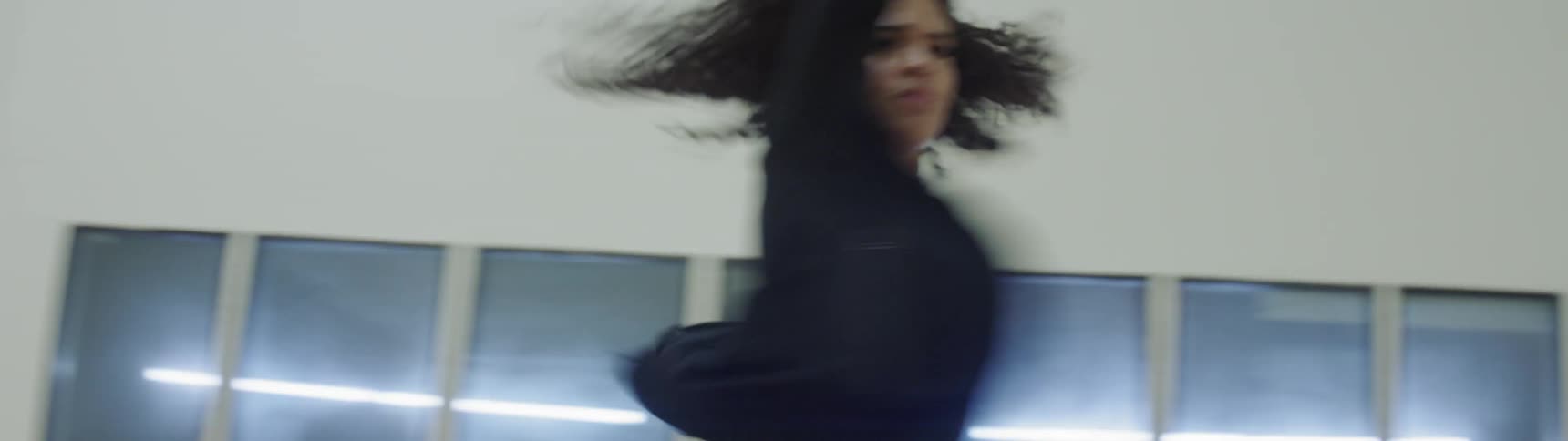 A young woman practices a dance in an empty room