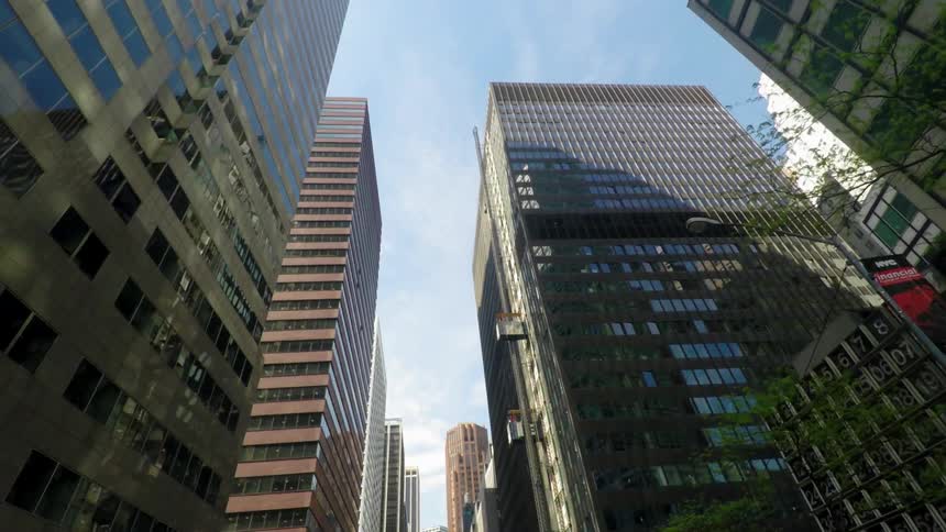 A row of tall buildings have reflective windows on a cloudy day