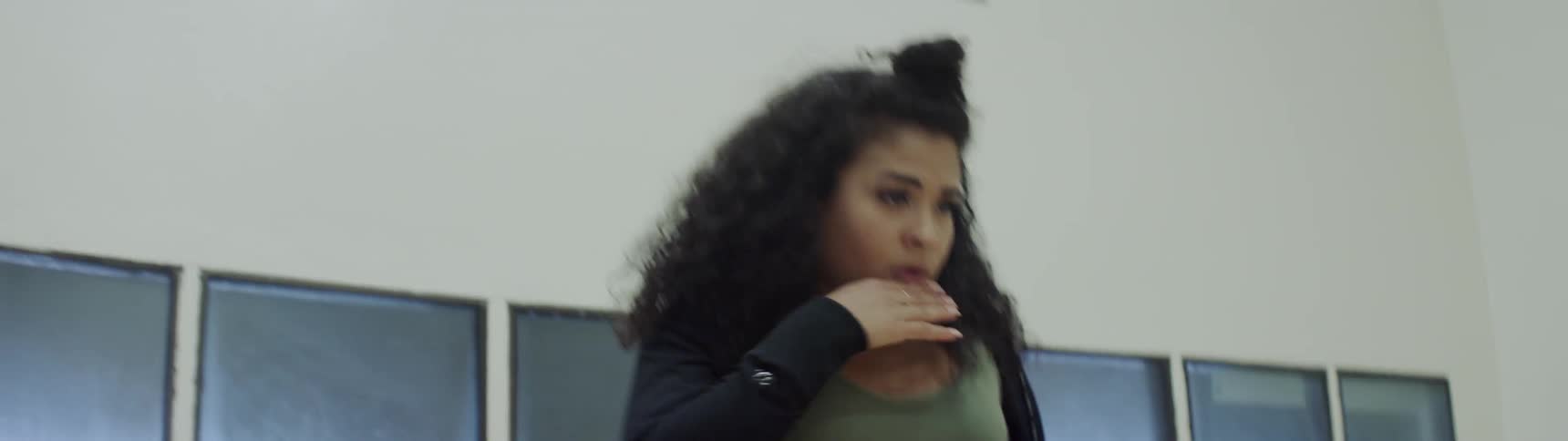 Curly hair girl leaning on wall prepares to dance in between four walls