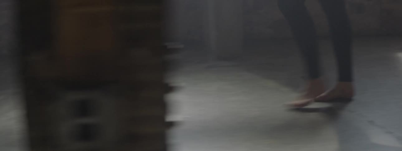 A white man walks barefoot on a concrete floor