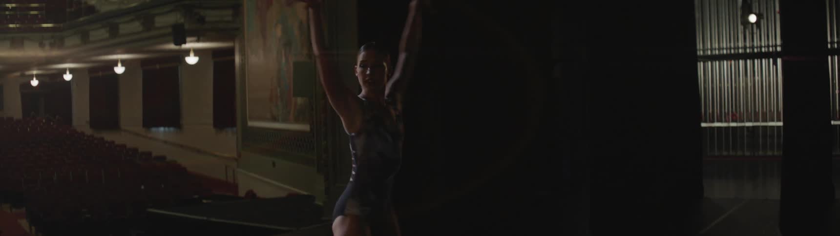 Female ballet dancer dances on stage in front of empty theater