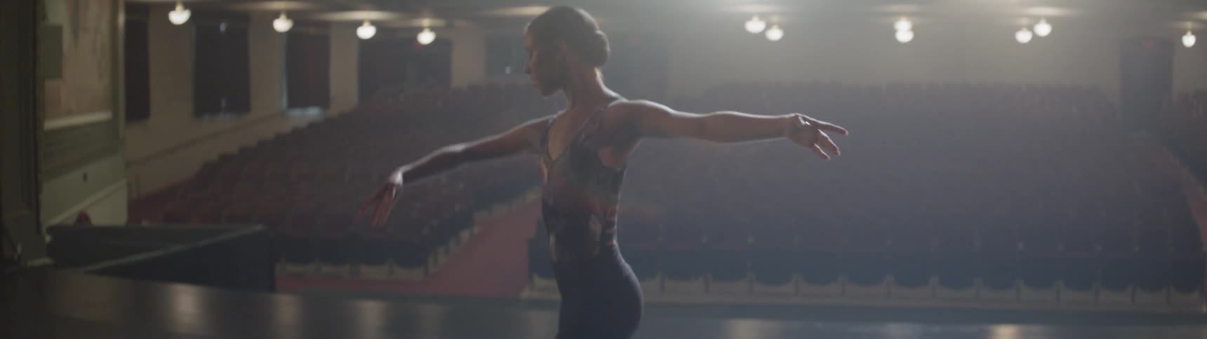 A woman is dancing with her arms out on stage