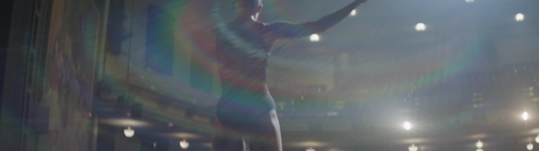 A woman dances under bright lights in a theater