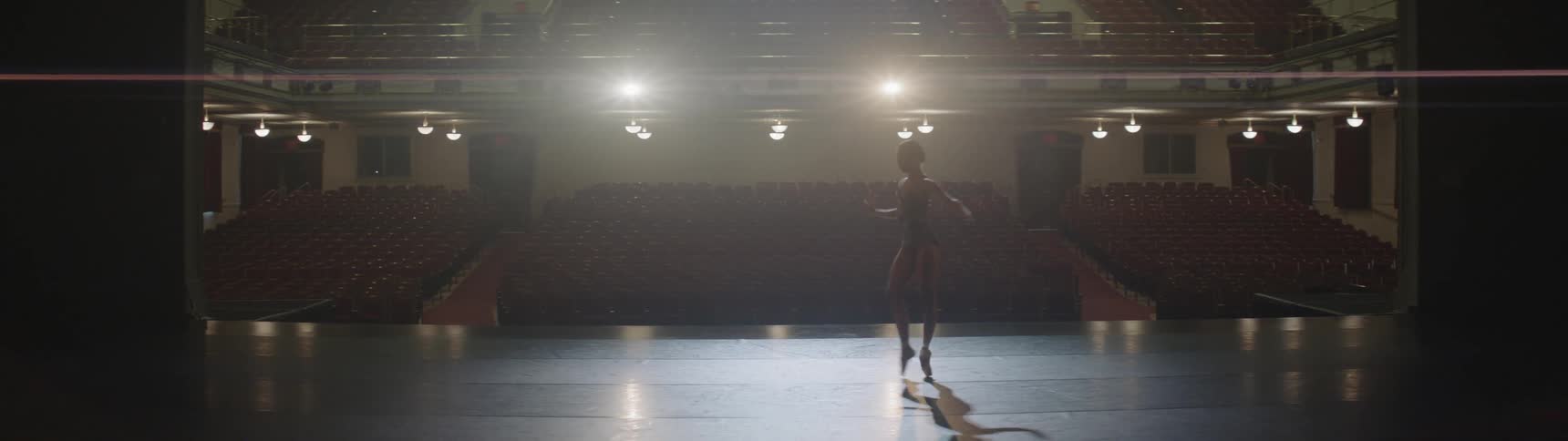 A woman is dancing indoors on a stage