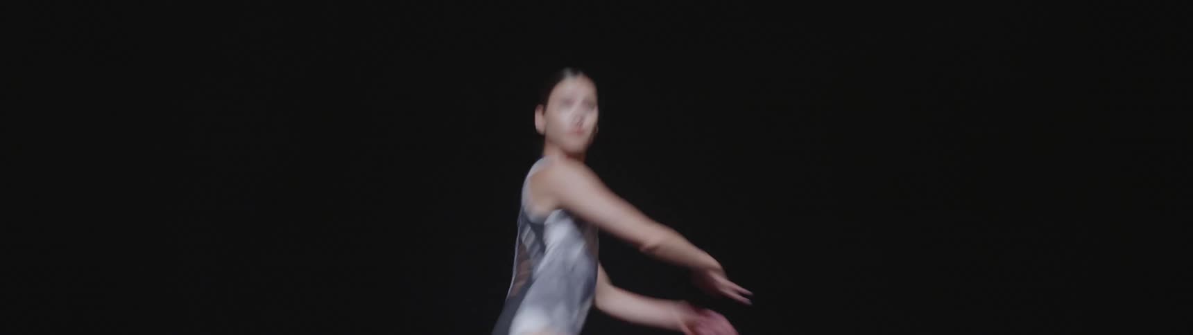 Girl performs ballet on the stage with dark background in the concert hall