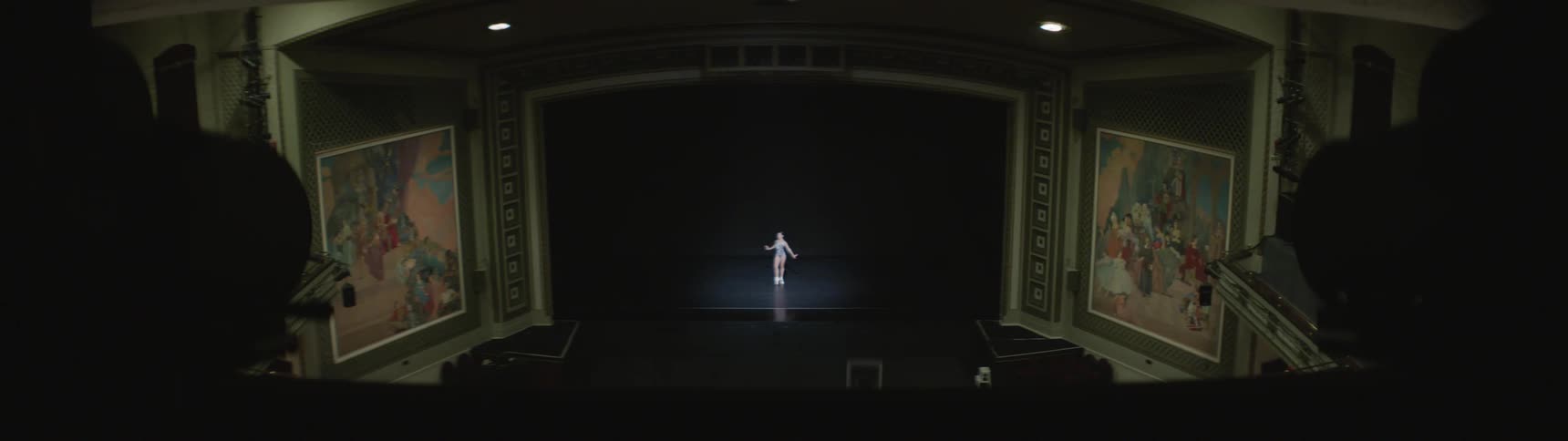 A ballerina dances on stage in a large auditorium