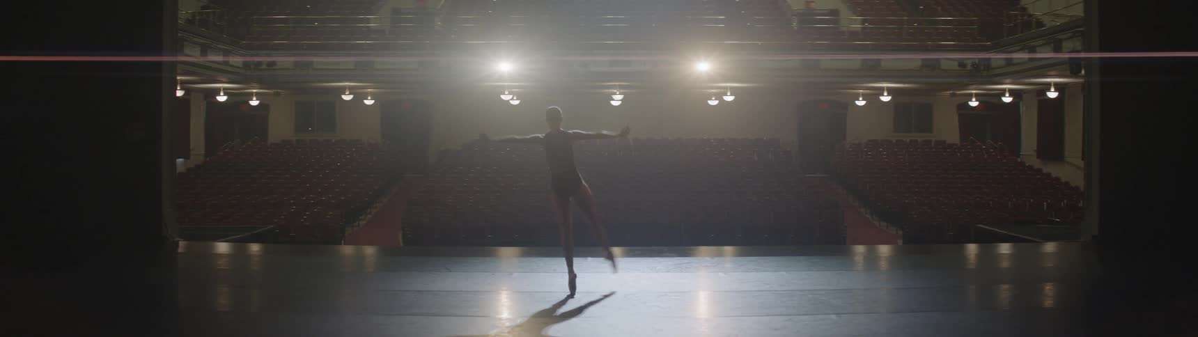 A woman dances on a brightly lit theater stage