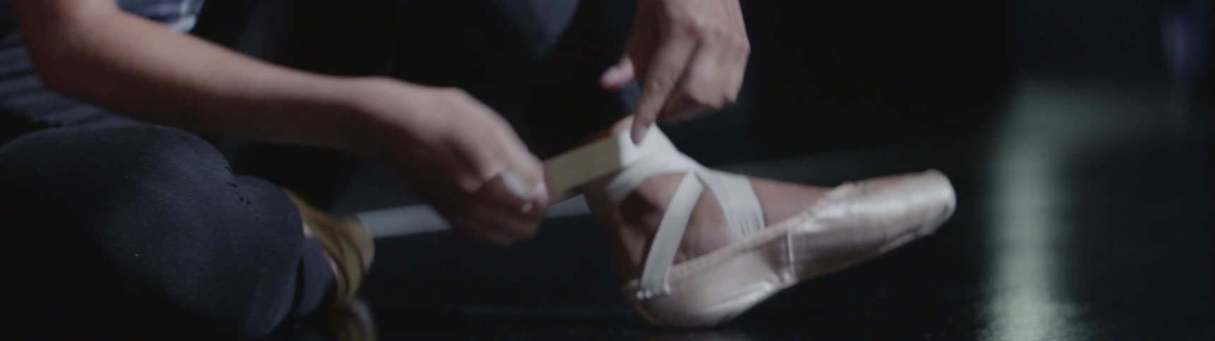 A ballerina ties her shoes
