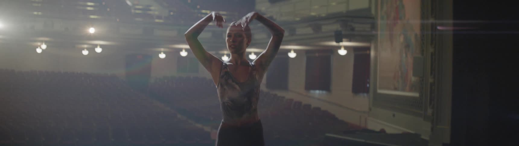 A woman practices ballet on a stage in an auditorium