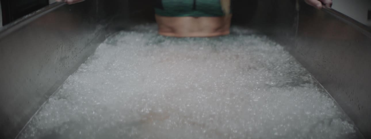 A woman is sitting in a tub filled with ice