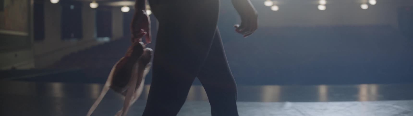 A ballerina walks along carrying her slippers