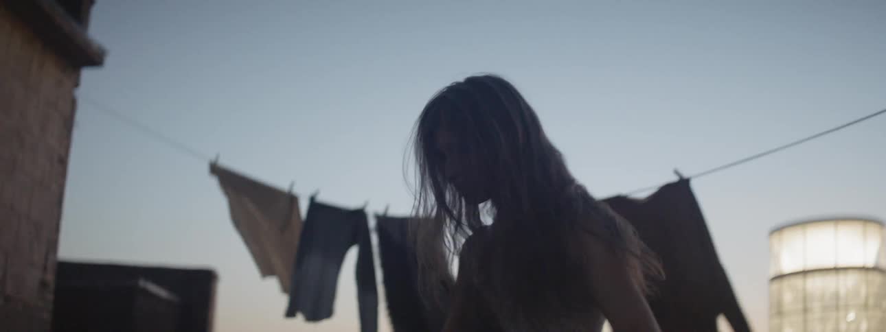 A woman in the rooftop dancing with the sky in the background