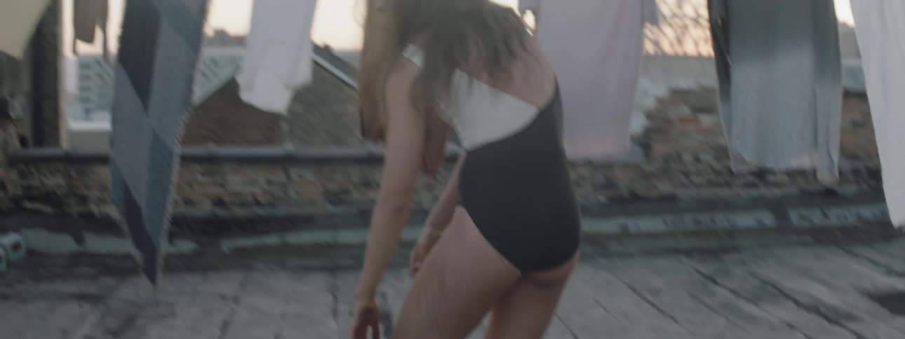A young woman dances beside drying laundry