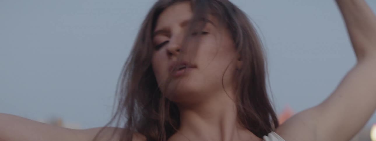 A woman dances with a city in the background