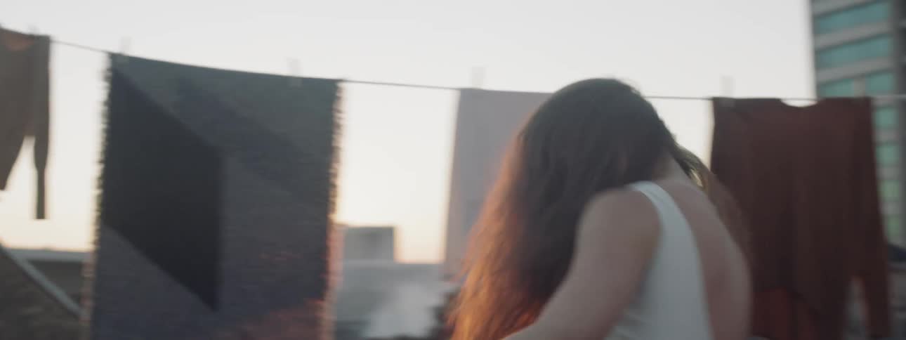 A woman dancing on a rooftop in a city