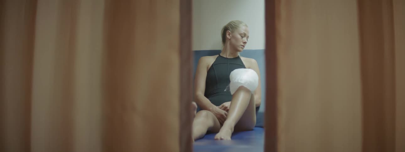 Woman sits on a floor and relaxes with an ice pack on her knee