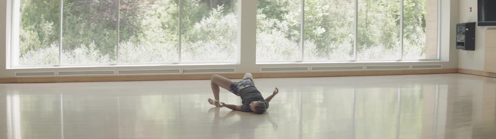 Girl performs ballet in a big gym during daylight